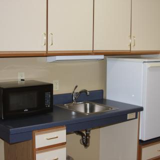 A compact kitchen area with cabinets, a microwave, sink, and refrigerator.