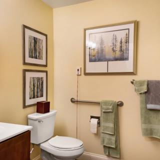 A well-decorated bathroom with wall art, towels, and a grab bar next to the toilet.