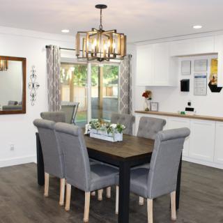 A modern dining room with a stylish chandelier and a wooden table surrounded by gray upholstered chairs.