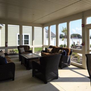 A cozy patio with comfortable seating and large windows allowing plenty of sunlight.