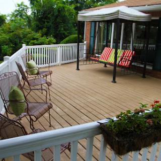 A serene outdoor deck furnished with comfortable seating and surrounded by lush greenery.