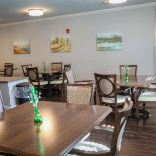A cozy dining area with neatly arranged tables and chairs, decorated with simple artwork on the walls.