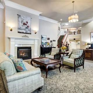 A beautifully designed living room featuring a cozy fireplace, elegant furniture, and a spacious layout with a staircase leading to the upper floor.