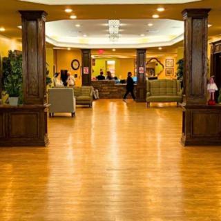 A spacious hotel lobby with a wooden floor and comfortable seating areas.