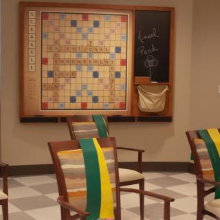 A game room featuring a large Scrabble board on the wall with chairs arranged nearby.