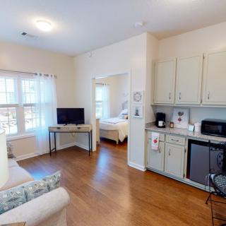 A cozy apartment interior featuring a small living area with a TV and an adjoining kitchen space.