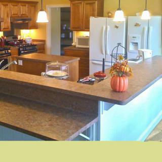 A modern kitchen with wooden cabinets and a central island, featuring pendant lights and seasonal decorations.