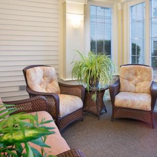 A cozy indoor seating area with wicker chairs and a potted plant by large windows.
