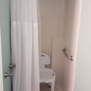 An accessible shower with a chair and safety grab bar.