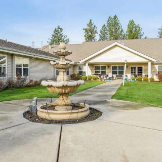 A scenic courtyard featuring a tiered fountain in front of a residence surrounded by greenery.