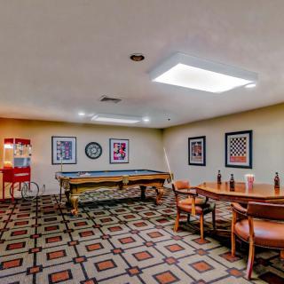 A cozy game room featuring a pool table, popcorn machine, and seating area with decorative artwork on the walls.
