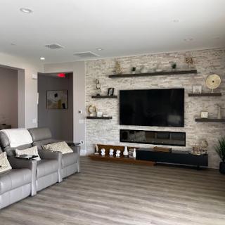 A modern living room featuring a cozy seating area, wall-mounted television, and stylish shelves.