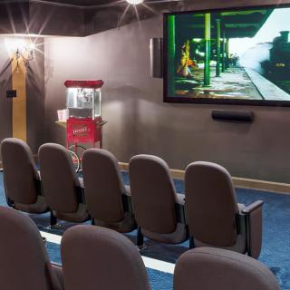 A cozy home theater setup with comfortable seating, a large screen, and a popcorn machine for an immersive movie experience.