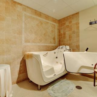 A bathroom featuring a walk-in bathtub with beige tiled walls and flooring.