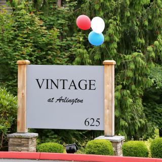 A sign for Vintage at Arlington with red, white, and blue balloons attached.