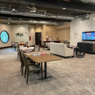 A modern office workspace featuring conference tables, chairs, a television, and stylish decor.