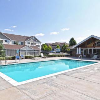 A residential complex with a large outdoor swimming pool on a sunny day.