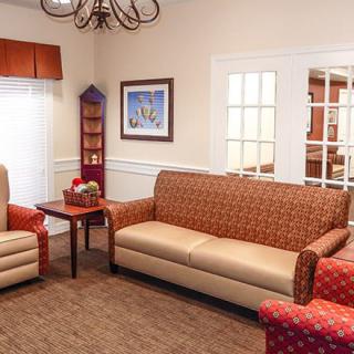 A cozy living room with a sofa, armchairs, and a coffee table, decorated with artwork on the wall.