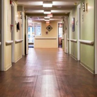 An empty institutional hallway with wooden floors and overhead lighting.