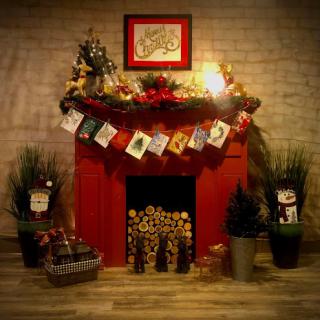 A beautifully decorated red fireplace, adorned with festive garlands and greeting cards, creating a warm holiday ambiance.