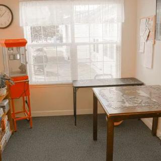A cozy room with tables and a puzzle, illuminated by natural light from a large window.