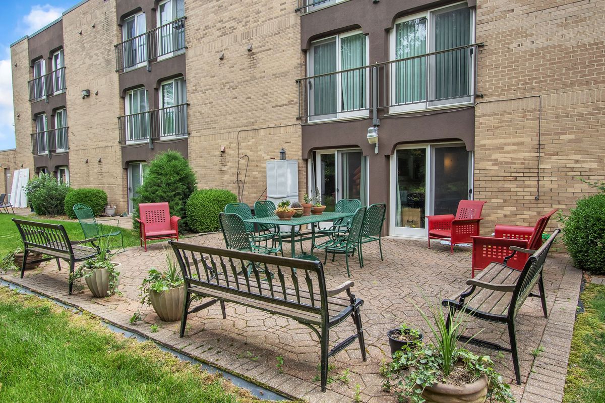 A cozy outdoor patio area with garden furniture and plants outside an apartment building.