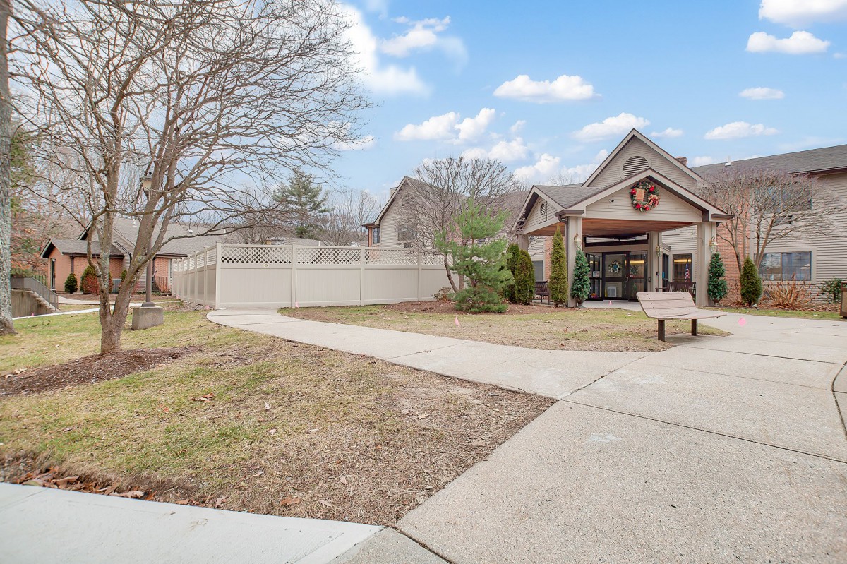 A residential house with a yard and sidewalk under a partly cloudy sky.