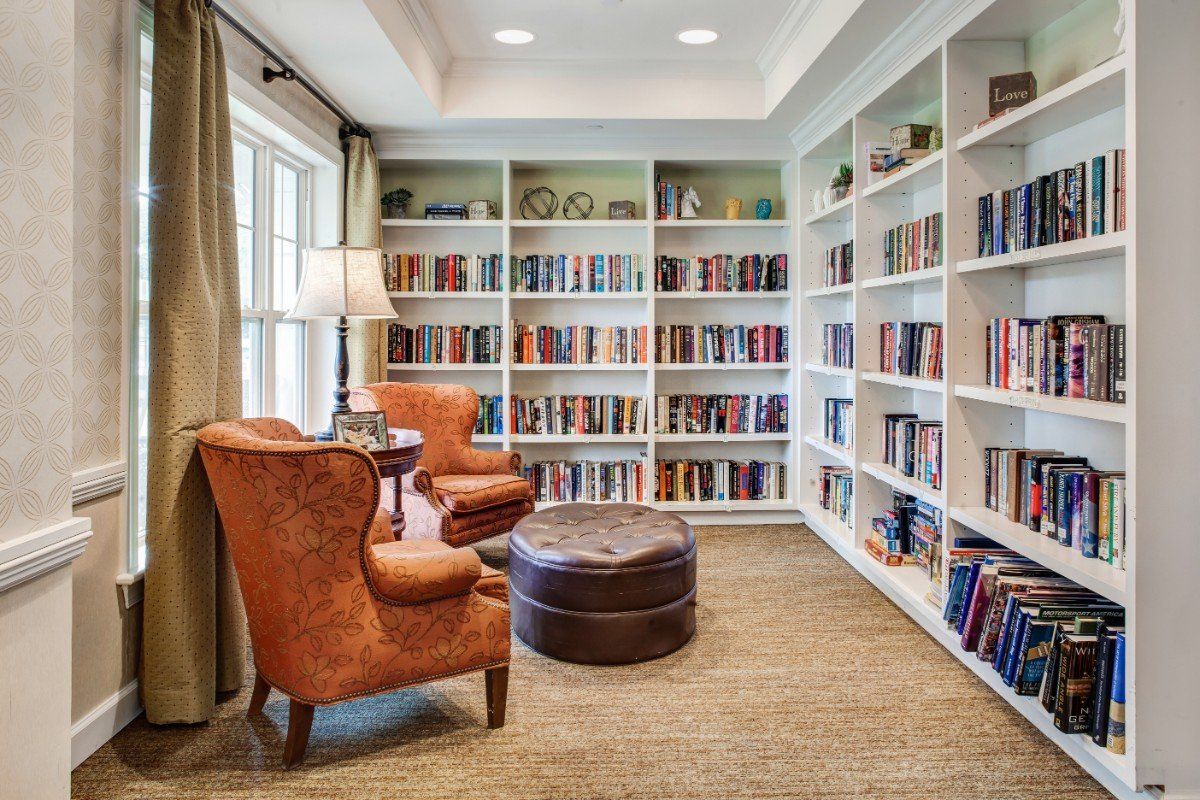 A cozy reading nook with armchairs and bookshelves filled with books.