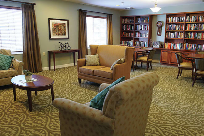 A cozy living room with bookshelves, comfortable seating, and warm lighting.