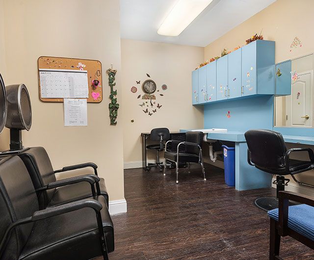A small office waiting area with chairs and a desk, featuring wall decor and storage cabinets.