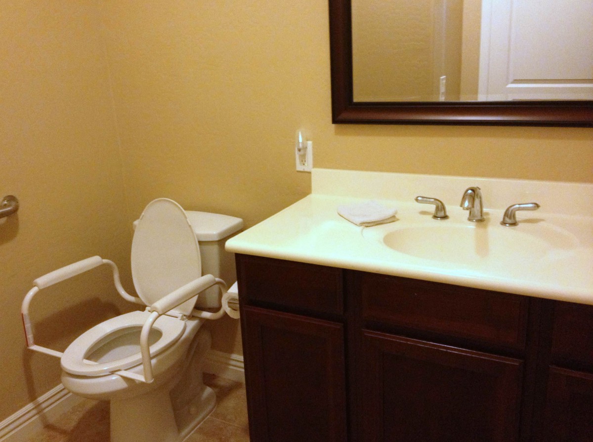 A clean and accessible bathroom with a toilet, sink, and mirror.