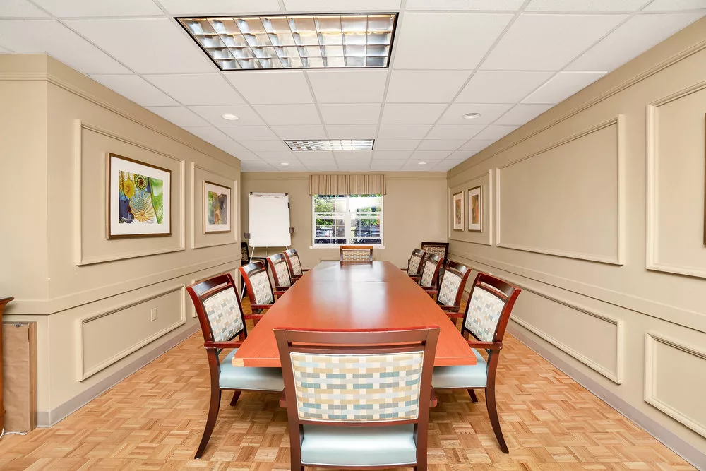 A well-furnished conference room with a long meeting table and chairs.