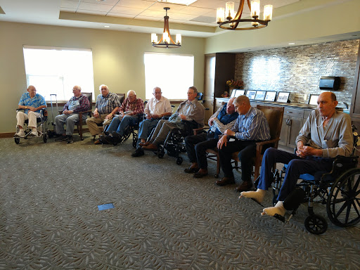A group of elderly individuals seated together in a community center, engaging in conversation.