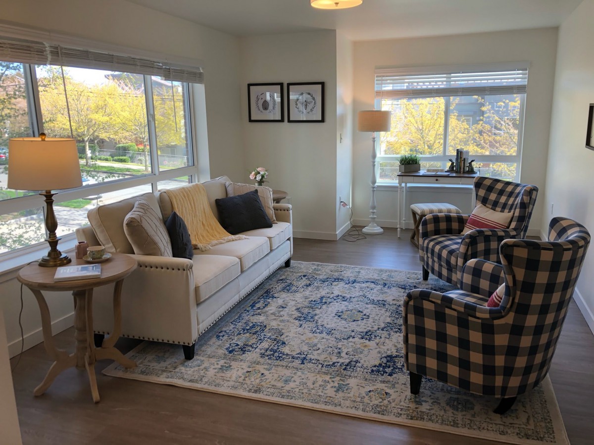 A cozy living room with a sofa, two armchairs, and large windows letting in natural light.