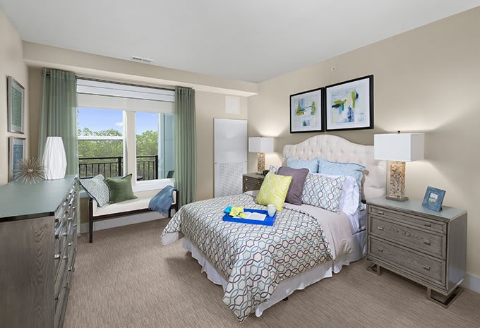 A modern and well-decorated bedroom featuring a large bed with patterned bedding, artwork on the walls, and a window offering a scenic view.