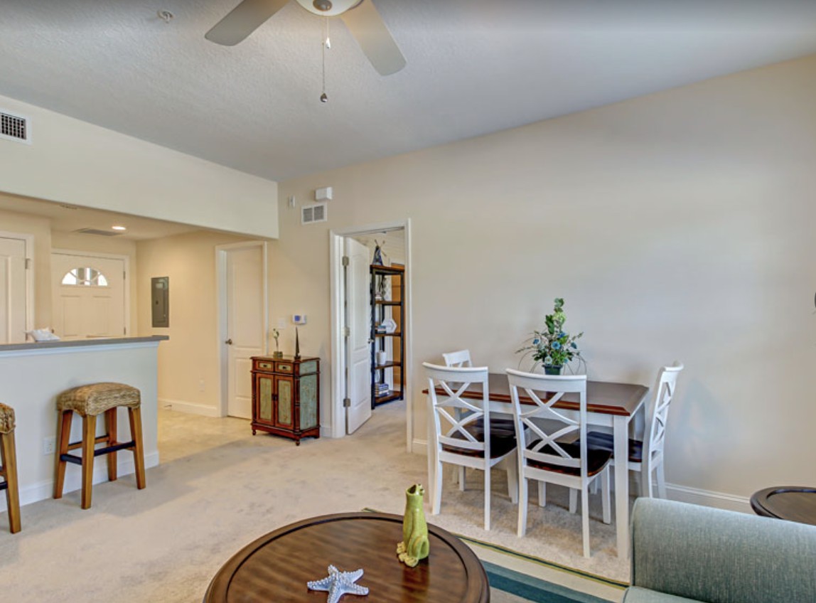 A cozy living and dining area with white furniture and warm lighting.