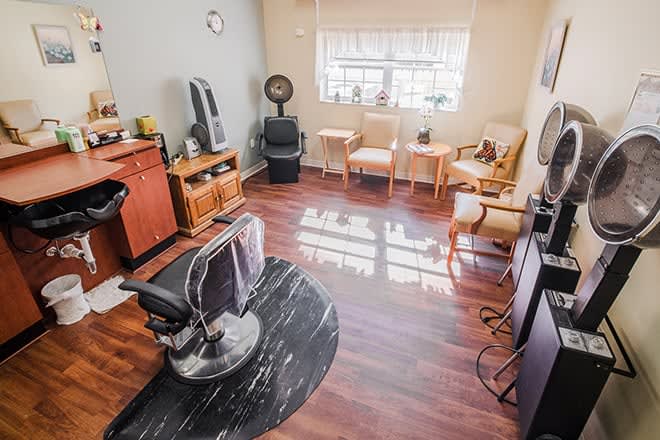 A cozy hair salon with a styling chair, mirrors, and a waiting area with sunlight streaming through the window.