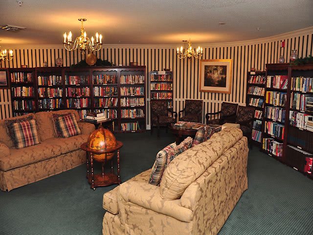 A cozy library room with bookshelves, comfortable sofas, and elegant chandeliers.