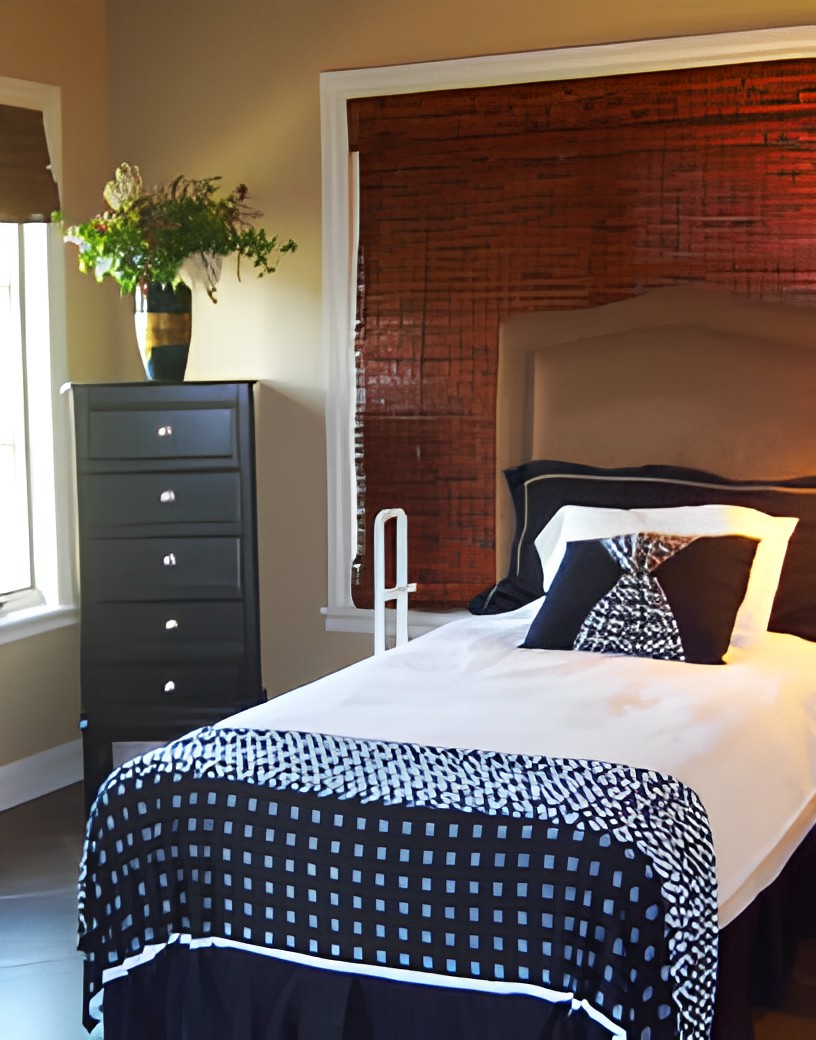 A cozy bedroom with a single bed, stylish bedding, and a dresser adorned with a vase of flowers.
