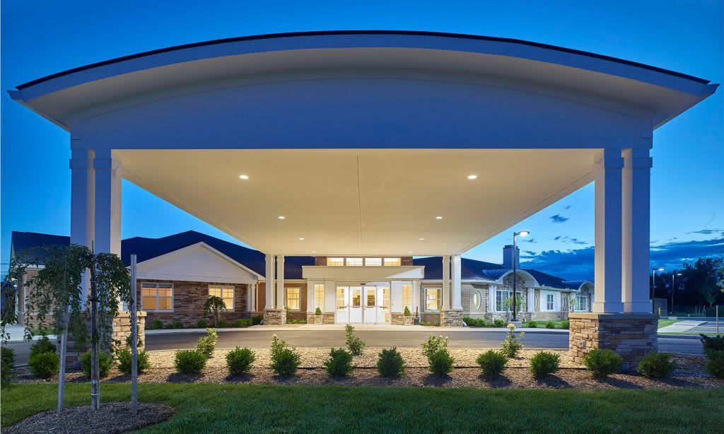 A modern building entrance illuminated at night with well-maintained landscaping.