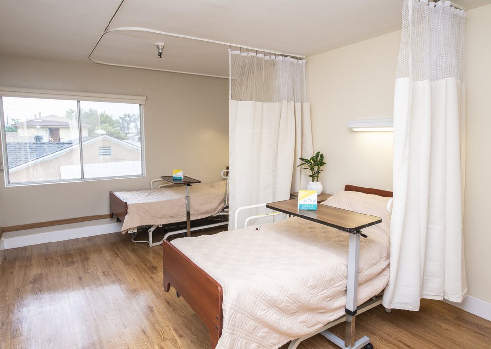 A quiet hospital room with neatly arranged patient beds and curtain dividers, providing a clean and organized healthcare environment.