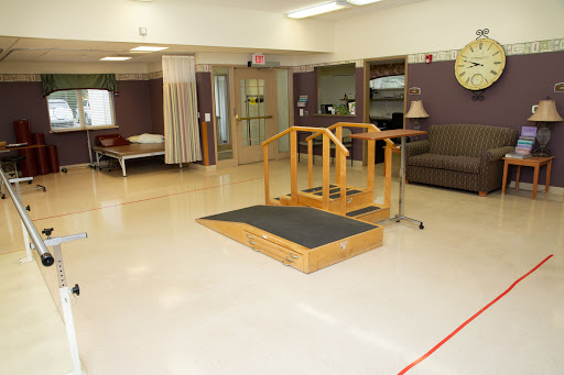 A rehabilitation therapy room featuring a wooden ramp with handrails, designed for patient mobility and accessibility.