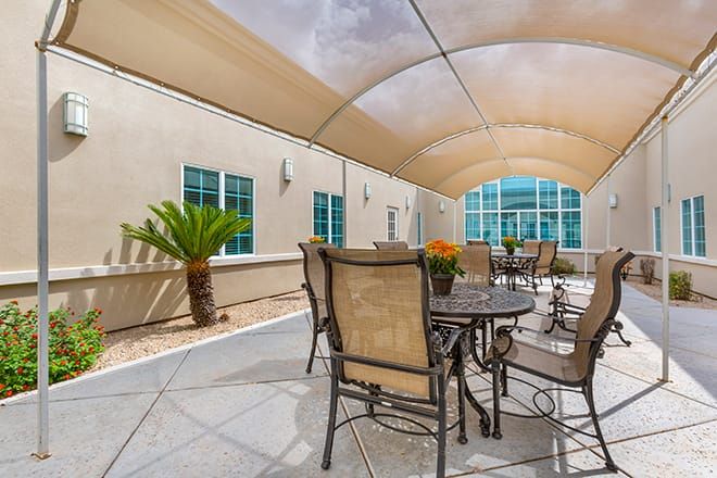 A shaded outdoor patio area with tables and chairs.