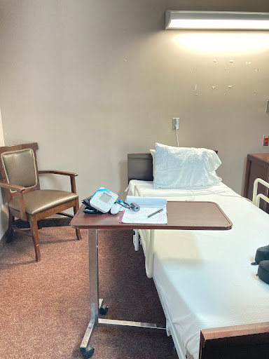 A serene hospital patient room with a bed, chair, and medical equipment.