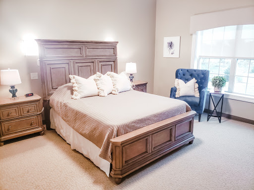 A cozy and elegantly furnished bedroom featuring a comfortable bed, stylish nightstands, and a blue accent chair.
