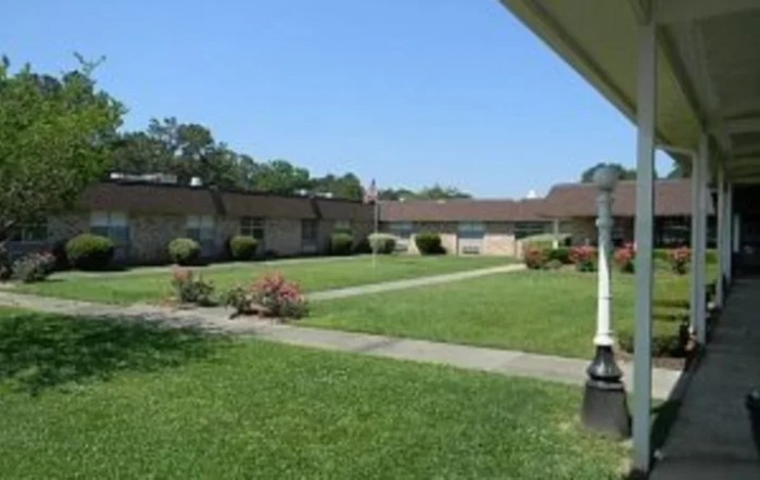 A view of a grassy courtyard surrounded by low buildings under a clear blue sky.