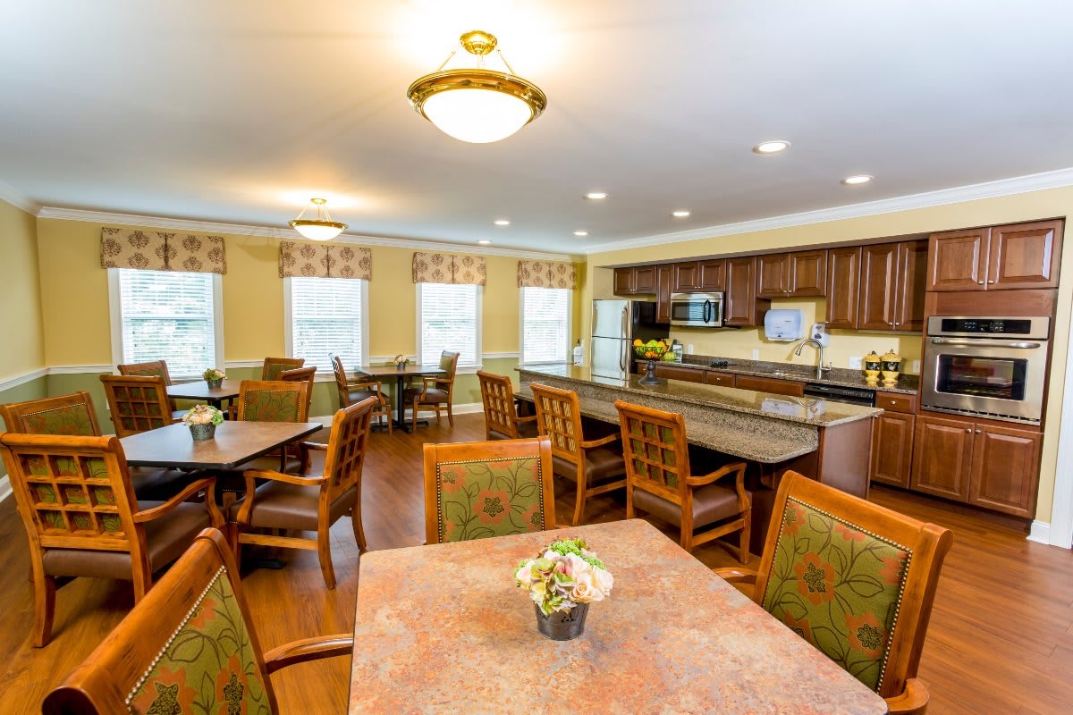 A cozy dining area with a kitchen, featuring multiple tables and chairs.