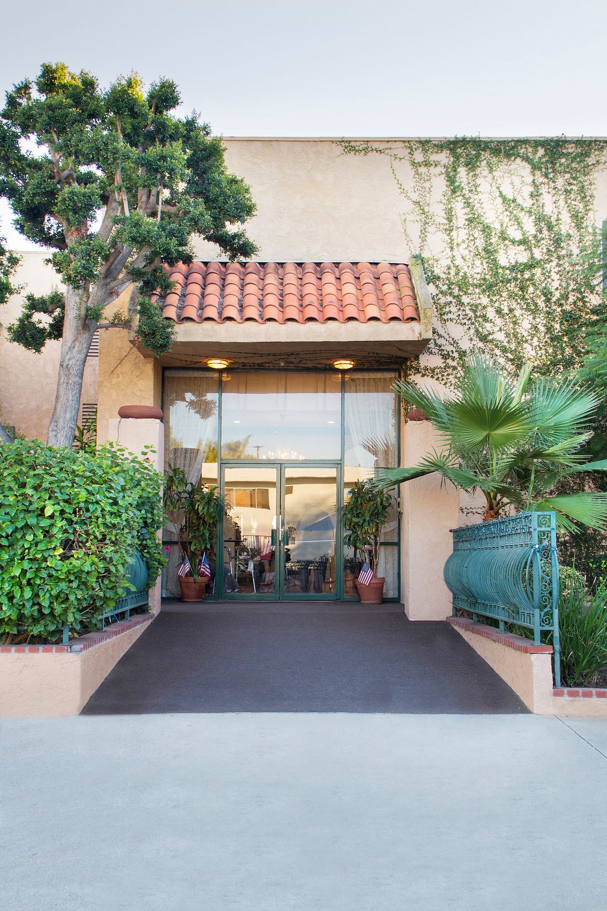 A building entrance with glass doors and surrounding greenery.