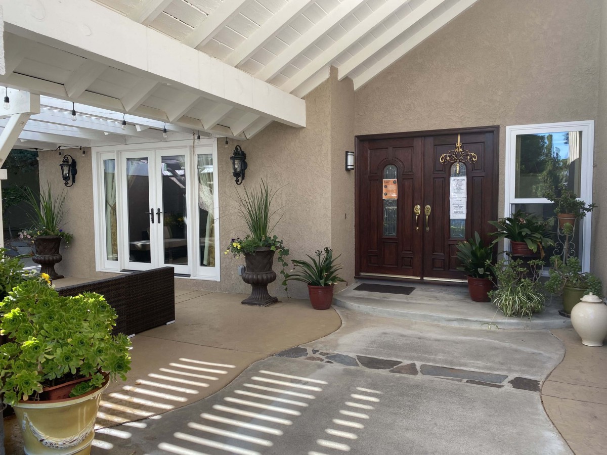 A welcoming house entrance with potted plants and outdoor seating.