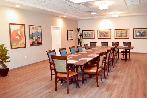 A spacious conference room featuring a long wooden table surrounded by chairs and decorated with framed artwork.